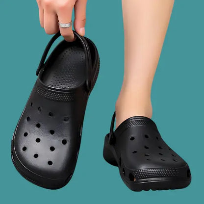 Black CrocsOrtho clogs held by hand, featuring breathable design and non-slip sole for comfort and style.