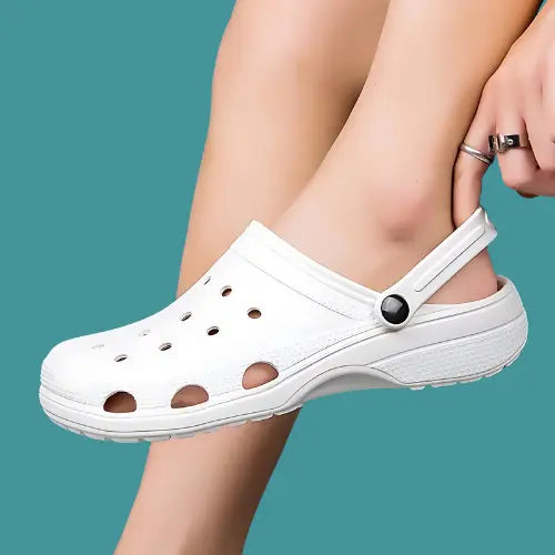 A close-up of a person wearing white CrocsOrtho clogs, highlighting the breathable design and comfortable fit.