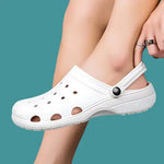 Load image into Gallery viewer, A close-up of a person wearing white CrocsOrtho clogs, highlighting the breathable design and comfortable fit.
